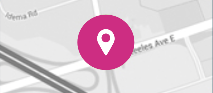 A map with a large magenta location pin icon centered over blurred street names and roads.