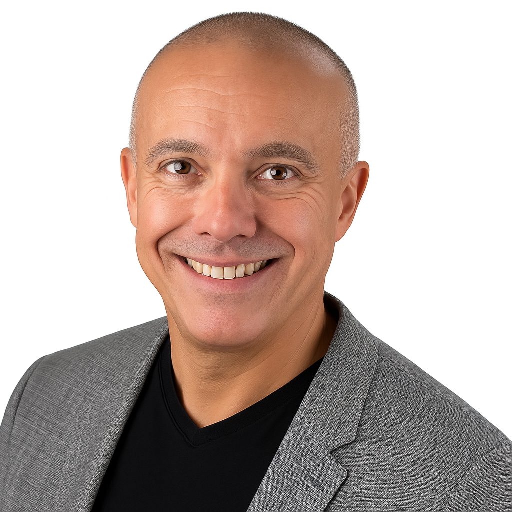 Smiling bald man wearing a gray blazer over a black shirt, posing against a plain white background.