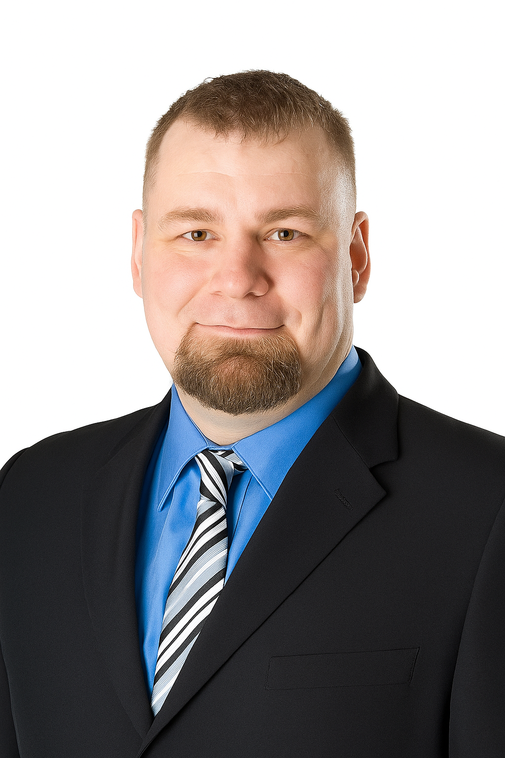 A man with short hair and a goatee, wearing a black suit, blue shirt, and striped tie, poses against a plain white background.
