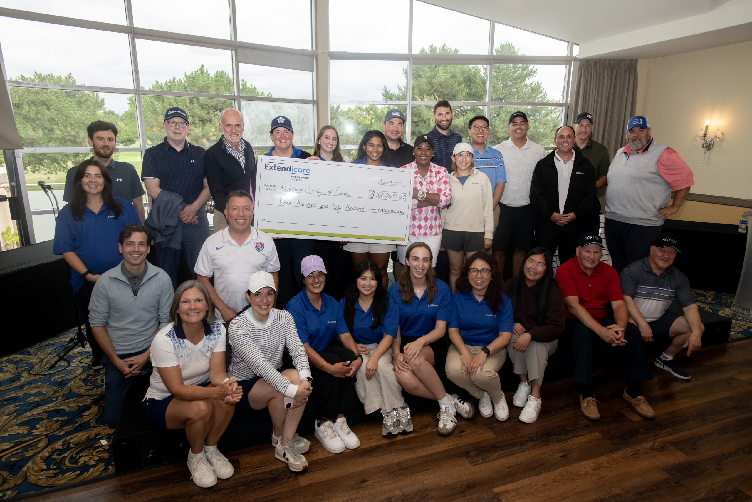 A group of people pose indoors holding a large check from Extendicare for $135,000 made out to the Extendicare Scholarship Program.